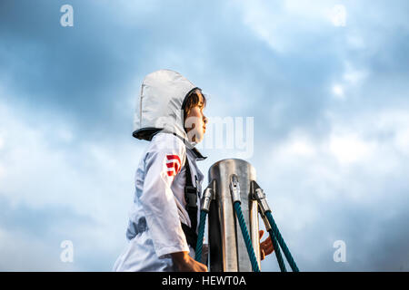 Portrait de jeune garçon en costume d'astronaute contempler du haut du mur d'escalade contre ciel dramatique Banque D'Images