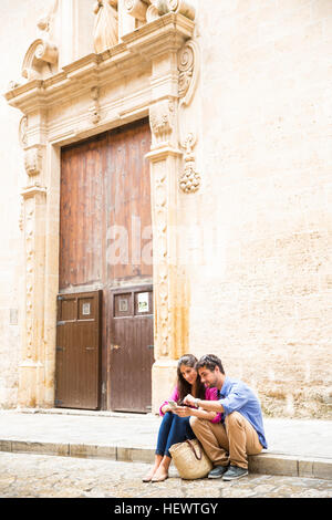 Couple using mobile phone on pavement, Palma de Mallorca, Espagne Banque D'Images