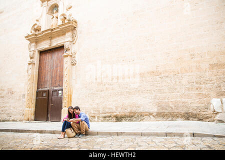 Couple using mobile phone on pavement, Palma de Mallorca, Espagne Banque D'Images