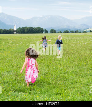 Vue arrière d'enfants courant dans le champ, Füssen, en Bavière, Allemagne Banque D'Images