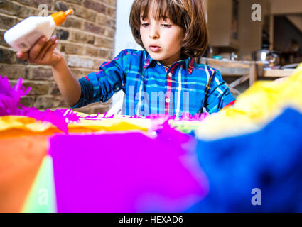 Boy diffusion de colle sur le papier crépon pour faire pinata Banque D'Images
