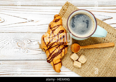 Des croissants frais et du café sur fond de bois Banque D'Images