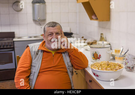 Portrait of senior man barbu assis sur une chaise dans la cuisine Banque D'Images
