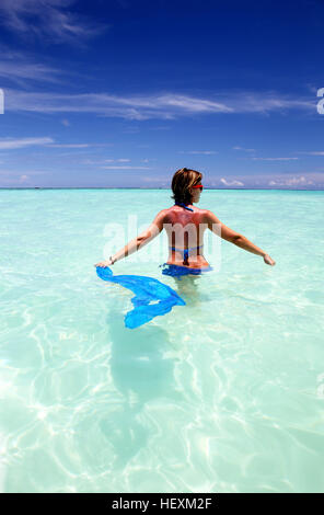 Les Maldives, femme debout dans l'eau peu profonde Banque D'Images