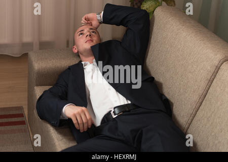 Beau Jeune homme en costume et cravate dormir ou se reposer dans le canapé Banque D'Images