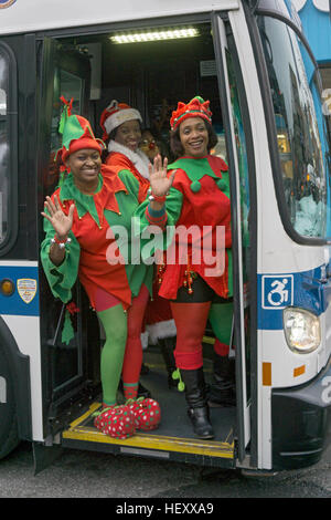 3 bénévoles de l'église habillés comme des elfes retour d'un party de Noël de charité pour les enfants. Au centre-ville de Flushing, Queens, New York. Banque D'Images