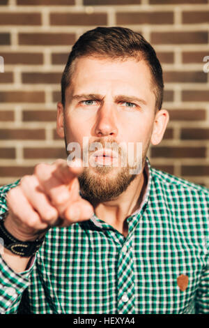 Jeune homme avec barbe et moustaches, doigt pointant vers l'appareil photo Banque D'Images