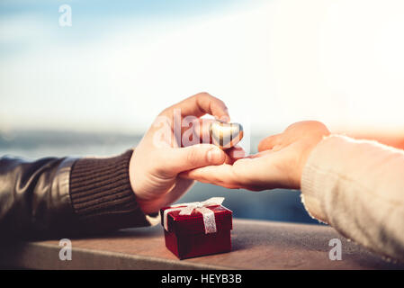 Couple holding hands sur le toit avec petite boîte cadeau rouge en premier plan Banque D'Images
