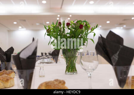 Thème noir et blanc table célébration simcha challah avec petits pains et vase de fleurs rose rouge Banque D'Images