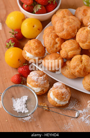 Profiteroles stuffed décoré avec des morceaux de fruits Banque D'Images