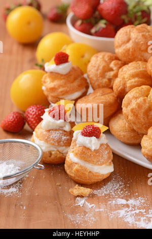 Profiteroles stuffed décoré avec des morceaux de fruits Banque D'Images