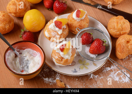 Profiteroles stuffed décoré avec des morceaux de fruits Banque D'Images