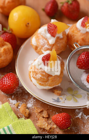 Profiteroles stuffed décoré avec des morceaux de fruits Banque D'Images