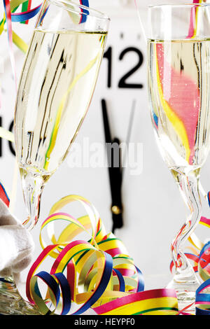 Deux verres de champagne avec du papier continu, d'horloge indiquant peu avant 12 h 00, minuit Banque D'Images