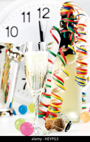 Verre et bouteille de champagne avec du papier continu, d'horloge indiquant peu avant 12:00 Banque D'Images