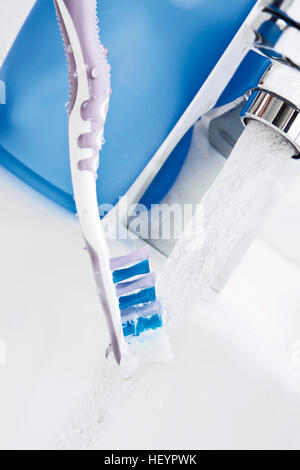 Brosse à dents sous l'eau du robinet en cours Banque D'Images