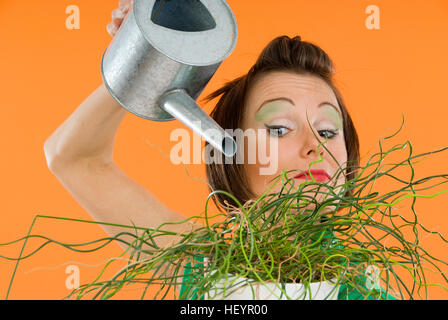 Jeune femme d'arroser une plante d'intérieur Banque D'Images