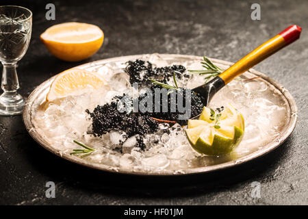 Cuillère à caviar noir sur la glace close up sur fond noir Banque D'Images