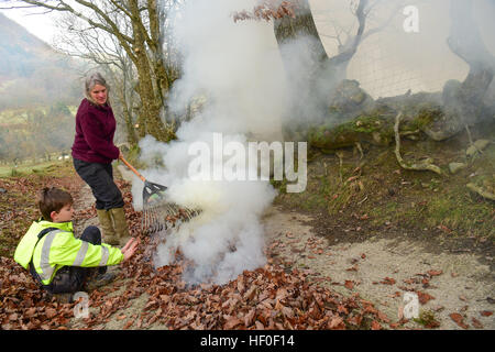 Llangynog, Powys, Wales, Royaume-Uni Le mardi 27 décembre 2016 par un froid glacial et matin dans Llangynog, un petit village au fond des montagnes Berwyn, au nord du Pays de Galles, KATE JEFFRIES, avec son petit-fils, William (11), ramasser et brûler les dérives de feuilles sèches qui se sont accumulés sur la piste de sa ferme à distance après le coup de vent et des tempêtes au cours de Noël Photo © Keith Morris / Alamy Live News Banque D'Images