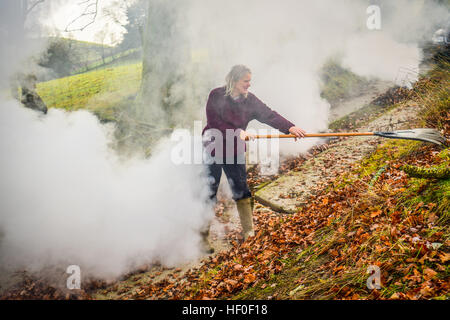 Llangynog, Powys, Wales, Royaume-Uni Le mardi 27 décembre 2016 par un froid glacial et matin dans Llangynog, un petit village au fond des montagnes Berwyn, au nord du Pays de Galles, KATE JEFFRIES, balaie et brûle les dérives de feuilles sèches qui se sont accumulés sur la piste de sa ferme à distance après le coup de vent et des tempêtes au cours de Noël Photo © Keith Morris / Alamy Live News Banque D'Images