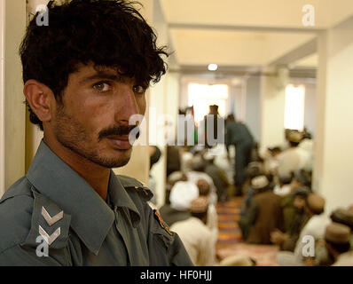 Le district de GARMSIR, province de Helmand, Afghanistan - un membre de la Police nationale afghane est à l'écoute de Garmsir forme Mohammed Fahim Gouverneur de District avant d'une cérémonie au siège de la Police du District, le 3 juillet. Il était parmi plus de 15 policiers de Garmsir pour recevoir des récompenses pour leur participation à la capture de deux individus de grande valeur recherché par 1er bataillon du 3e Régiment de Marines. À la fin de mai, l'ANP a remporté quatre insurgés, dispositif explosif de matières et d'armes nucléaires dans le cadre de contrôle des véhicules dans l'est du désert de Garmsir. La police Garmsir reconnu Banque D'Images