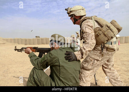 Un instructeur de la marine guide une recrue de la police locale afghane au cours d'une formation au tir dans un champ de tir sur les armes légères lors d'un cours académique soutenu par le Ministère de l'intérieur, où des recrues de plusieurs villages ont suivi une formation de plusieurs jours. Banque D'Images