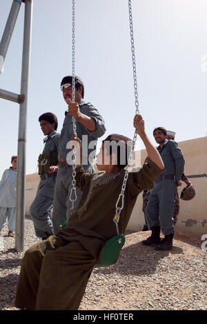 Un enfant afghan ressemble à un membre de la police en uniforme afghane comme il essaie d'un nouveau swing au Delaram Boy's High School, 17 mai 2012. Les membres de l'arrondissement du centre d'AUP installé la balançoire. Une douzaine de policiers est venu à l'école pour distribuer des livres, des vêtements et des équipements sportifs. Près de 800 garçons de 6e 5 - 11 participer à l'école. La police afghane construire ensemble d'oscillation pour l'école de garçons 120517-M-MS345-020 Banque D'Images