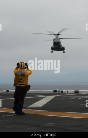 La Marine américaine membre d'équipage de signaux a U.S. Marine Corps CH-46E Sea Knight helicopter attaché à la 15e unité expéditionnaire de Marines à la terre pendant les opérations de vol à bord de l'USS Peleliu, Californie, le 22 juillet 2012.(U.S. Marine Corps photo par Lance Cpl. Danny L. Shaffer/ libéré) USS Peleliu 120722-M-BM539-013 Banque D'Images