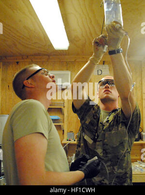 Circuit de l'armée américaine. Ross Cole (à gauche) et le Sgt. Brandon Green (à droite), les membres du 1er Bataillon, 6e Régiment d'artillerie, se préparer pour les fluides de traumatismes le 21 juillet 2013, à la base d'opérations avancée de Spin Boldak, Afghanistan. Les patients ont été victimes d'un bombardement à Spin Boldak, une ville voisine. (U.S. Photo de la Garde nationale par la CPS. Jovi Prevot) des soldats américains prendre soin des blessés Afghans 130721-Z-IX952-323 Banque D'Images