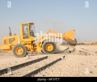 Un chargeur frontal est utilisé pour enlever les débris et bloquer l'accès à un site de décharge illégal à Ar Ramadi, en Iraq, dans le cadre des efforts de nettoyage et de reconstruction municipaux visant à améliorer l'assainissement et la gestion des déchets. Banque D'Images