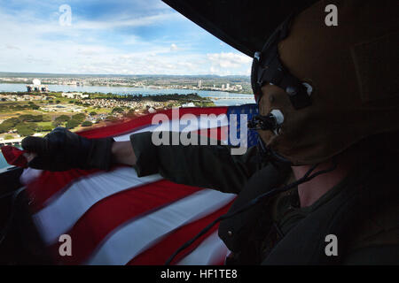 Lance le Cpl. Travis Paul, chef d'équipe avec l'hélicoptère d'attaque léger Marine 367 Escadron, permet de maintenir un drapeau américain sur le côté d'un hélicoptère Huey UH-1Y comme il vole au-dessus de l'USS Missouri, 5 décembre 2013. L'unité a effectué le survol sur Pearl Harbor, à Hawaï, où "Scarface" anciens étaient présents pour regarder la vitrine. (U.S. Marine Corps photo par Lance Cpl. Matthew Bragg) 'Scarface' anniversaire marque 70 ans dans le corps 131205-M-DP650-006 Banque D'Images