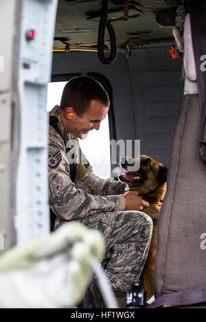 Tech. Le Sgt. Andrew Montgomery, un groupe de militaires de l'Armée de l'air de chien, console son chien à l'intérieur Diesel une armée UH-60 Blackhawk hélicoptère exploité par une compagnie, 3e Bataillon, 142e Assault Helicopter Company, 42e Brigade d'aviation de combat, au cours d'un exercice de familiarisation pour les chiens, le 10 janvier 2014, quelque part dans le sud-ouest de l'Asie. Les chiens de travail peuvent être transportés par hélicoptère rapidement et efficacement à l'endroit où ils sont nécessaires une fois qu'ils se sentent à l'aise avec l'avion. La 42e CAB, New York, la Garde nationale est actuellement déployé à l'étranger dans le cadre de l'opération Enduring Freed Banque D'Images