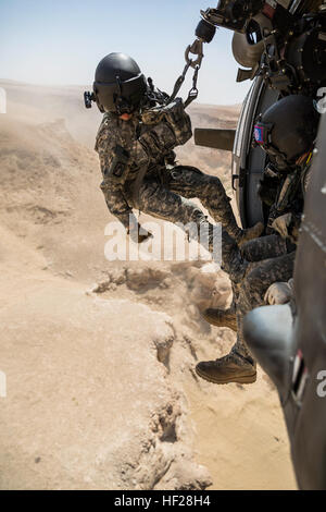 La CPS. Mouyos Nicholas, un médecin de vol, est abaissée par un palan à une victime simulée par la CPS. Giles Dunlop, chef d'équipe, au cours d'un exercice de récupération du personnel entre un UH-60 Black Hawk piloté par la société C, 1er Bataillon, 214e Air Ambulance, 42e Brigade d'aviation de combat (cabine), et une Koweïtienne SA 330 Puma de l'armée de l'air hélicoptère, 19 juin 2014, au Koweït. La 42e CAB et forces koweïtiennes effectuent régulièrement des joint aviation partenariats pour accroître leur capacité à répondre à toute urgence. La 42e CAB, New York, de la Garde nationale de l'armée est déployée au Koweït dans le cadre de l'opération Enduring Freedom. (New York) N de l'armée Banque D'Images