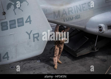 Un Marine avec des marines de l'escadron 161 à rotors basculants moyen (renforcée), 15e Marine Expeditionary Unit, se tient près de son MV-22B Osprey tandis qu'il y a une pause dans l'action à bord de la plate-forme de vol de l'USS Essex (LHD-2) au cours de l'exercice de l'unité de formation Composite (COMPTUEX) 18 mars, 2015. Les marines sont en cours de chargement de l'équipement et du personnel requis pour leur prochaine mission - Comptuex est conçu pour aider les marins et Marines pour intégrer leur déploiement à venir au printemps. (U.S. Marine Corps photo par le Cpl. De Clerck McKelvey/libérés) Ospreys prendre plus de 150318-M-JT438-195 Banque D'Images