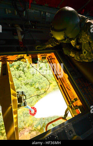 Une garde nationale d'armée de la Californie avec la Compagnie Bravo, 126e vol Chinook, observe hors de la trappe d'un hélicoptère Chinook à l'assemblée annuelle de l'entraînement des pompiers sur les feux de Californie le 12 avril 2015, en Californie Le guardsman se prépare à libérer l'eau d'un Bambi benne montée sur le ventre de l'avion. (U.S. Photo de la Garde nationale aérienne Aviateur Senior Rachael Kane) Cal-Fire - Formation Incendie Seau Bambi 150412-Z-FO231-112 Banque D'Images