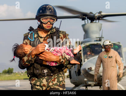 Un soldat népalais porte une jeune victime d'un tremblement du Corps des Marines américains UH-1Y hélicoptère Venom affecté à la Force opérationnelle 505 d'une zone de triage médical à l'aéroport international de Tribhuvan, Katmandou, Népal, après un séisme de magnitude 7,3 a frappé le pays, le 12 mai. 505 Groupe de travail conjoint avec d'autres forces multinationales et les organismes humanitaires sont en ce moment dans le Népal en fournissant de l'aide après un séisme de magnitude 7,8 a frappé le pays, le 25 avril. À la demande du Népal le gouvernement américain a ordonné la FOI 505 pour fournir des capacités uniques pour aider le Népal. (U.S. Marine Corps phot Banque D'Images
