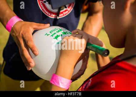 Un enfant avec le programme d'aide pour les survivants tragédie (TAPS), écrit un message lors d'un événement de lancement de ballons sur base du Corps des Marines, La Baie de Kaneohe, Hawaii le 28 février 2016. Les membres survivants de la famille a écrit des messages spéciaux sur les ballons qui ont été libérés plus tard au ciel hawaiien en souvenir du passé. (U.S. Marine Corps Combat Camera photo par le Cpl. Wesley Timm/libérés) et amis participant à se rappeler les robinets 12 Marines du HMH-463 160228-M-AR450-039 Banque D'Images