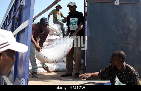 Des bénévoles locaux de Carrefour et de la région de Port-au-Prince qui travaillent pour le développement de l'Agence adventiste de secours, sacs de riz de déchargement d'un camion, à un site de distribution alimentaire à Carrefour, Haïti, le 12 février 2010. Les Marines du bataillon de l'équipe d'atterrissage, 3e Bataillon, 2e Régiment de Marines, 22e Marine Expeditionary Unit, et les forces de sécurité de l'ONU aident l'ADRA et le Programme alimentaire mondial au cours de leur grande distribution de deux semaines au cours de la première moitié de février 2010. 22e Marine Expeditionary Unit, l'ONU aide les organismes de secours non gouvernementaux dans la distribution des secours DVIDS251339 Banque D'Images