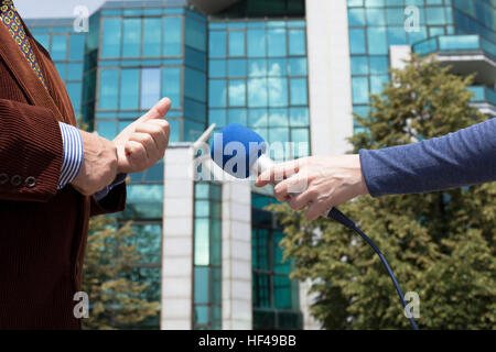 Homme d'entreprise, journaliste interviewant building en arrière-plan Banque D'Images