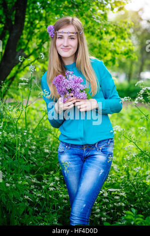 Belle jeune femme avec un bouquet de lilas en mains Jardin de printemps Banque D'Images