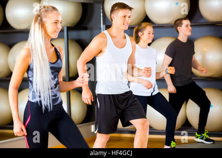 Groupe d'entraînement motivés sauts à plates-formes dans une salle de sport Banque D'Images