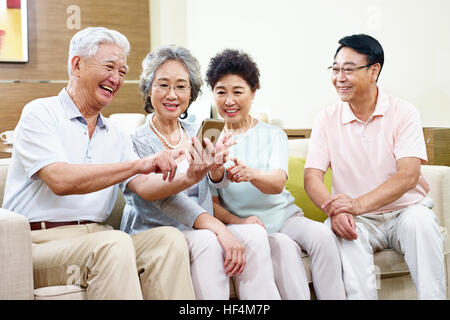 Petit groupe de personnes d'Asie senior en partageant du contenu cellulaire au cours de la cueillette. Banque D'Images