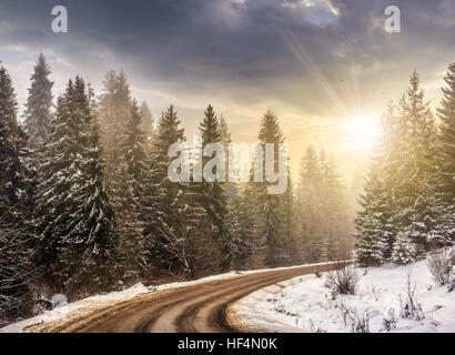 Paysage de montagne d'hiver. route sinueuse qui mène à la forêt de sapins couverts de neige dans la lumière du soir Banque D'Images