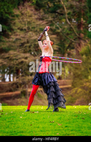 Belle jeune femme en costume de cirque jouer avec cerceau dans le parc. Banque D'Images