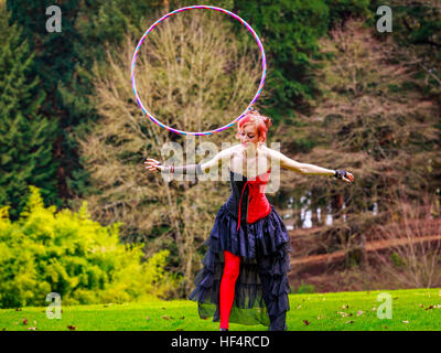 Belle jeune femme en costume de cirque jouer avec cerceau dans le parc. Banque D'Images