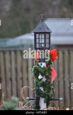 Un lampadaire décoré dans des couleurs de vacances vu dans une tempête d'hiver. Banque D'Images