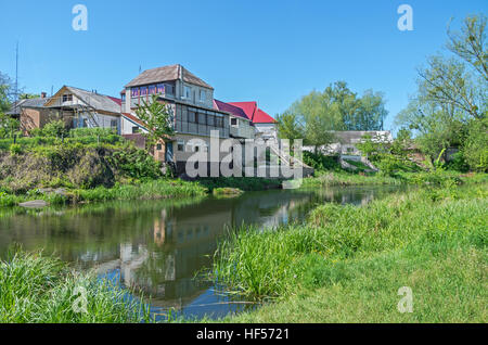 Une petite maison près d'une rivière entourée d'arbres printemps chaud jour Banque D'Images