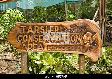 Un panneau en bois sculpté points à l'entrée de la zone de conservation Tarsier dans l'île de Bohol, Loboc, Philippines. Banque D'Images