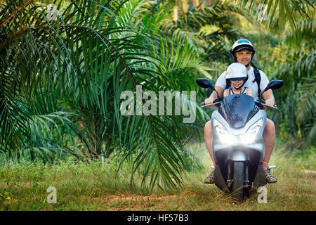 Père et son petit fils équitation moto sur route au cours de la jungle tropicale island vacation en Asie Banque D'Images