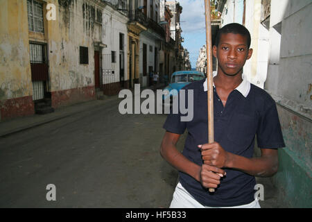 Garçon portant un bâton de baseball fait maison debout sur une rue de La Havane, Cuba, Caraïbes, Amériques Banque D'Images